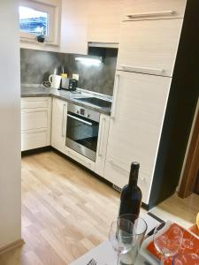 una cocina con armarios blancos y una botella de vino en Cozy 2.5 Apartment with Swimmingpool, en Attalens