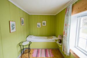 a small green room with a bed and a window at Handelsstedet Forvik in Vevelstad
