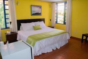 a bedroom with a large bed with yellow walls and windows at Ecohotel La Casona Pereira in Pereira