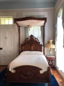 um quarto com uma cama de madeira e um dossel em The Montgomery B&B em Starkville