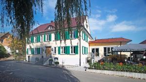 a white building with green shutters on a street at Hotel & Gutsgasthaus Köberle in Lindau
