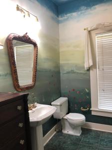 een badkamer met een toilet, een wastafel en een spiegel bij The Montgomery B&B in Starkville