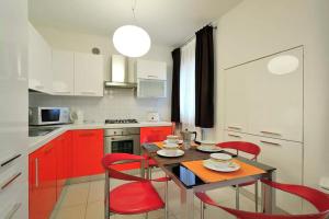 a kitchen with red cabinets and a table with red chairs at Red House ai Mori in Venice