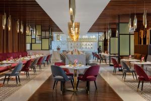 jadalnia ze stołami i krzesłami w obiekcie Dusit Doha Hotel w mieście Doha
