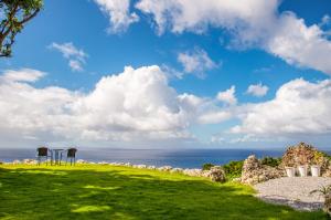 ein Grasfeld mit zwei Auslegungszeichen vor dem Meer in der Unterkunft Hanalee Villa Kouri in Nakijin