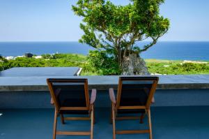 two chairs sitting on a balcony looking out at the ocean at Hanalee Villa Kouri in Nakijin