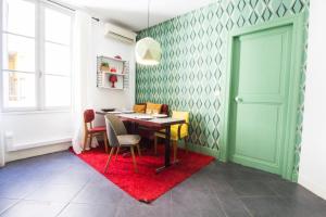 a dining room with a table and chairs on a red rug at Le comédien - Climatisation Place de la comédie in Montpellier