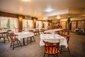 a restaurant with white tables and chairs and windows at St Georges Motor Inn in Melbourne