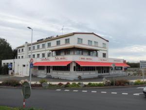 um edifício branco com um toldo vermelho numa rua em Hôtel Le Sully La Roche Sur Yon em La Roche-sur-Yon