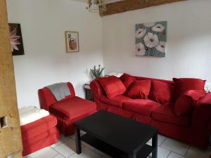 ein Wohnzimmer mit einem roten Sofa und einem Stuhl in der Unterkunft Les Gites de la Renardière in Gueures