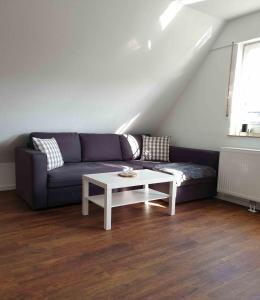 ein Wohnzimmer mit einem lila Sofa und einem Tisch in der Unterkunft Ferienwohnung Marlena in Hage