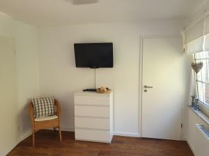 Zimmer mit einem TV an der Wand und einem Stuhl in der Unterkunft Ferienwohnung Marlena in Hage