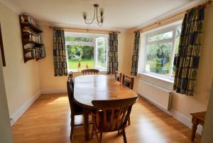 a dining room with a table and chairs and two windows at Woodside Cottage in Godshill