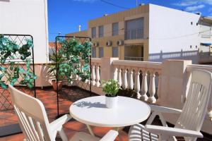 patio con mesa blanca y sillas en el balcón en Playa Pau Pi Eivissa AP945, en Oliva