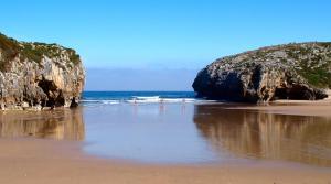 a beach with two large rocks and the ocean at Apartamentos El Castañeu in Corao