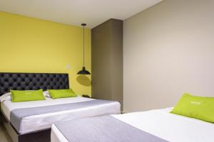 um quarto com 2 camas e almofadas verdes em 3H hotel centro histórico em Medellín