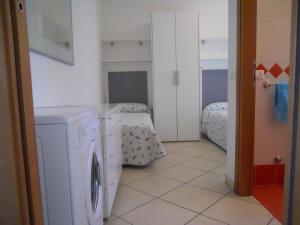 a laundry room with a washing machine and a bed at Villaggio Tulipano in Bibione