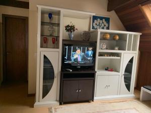 un centro de entretenimiento con TV en la sala de estar en Apartamento Castelinho - Centro, en Gramado