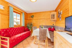 a living room with a red couch and a table at Blockhaus Ganschitter in Grossarl