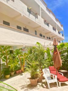 a hotel patio with chairs and plants and an umbrella at Suites Fenicia in Playa del Carmen