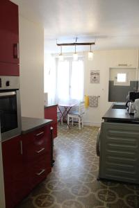 - une cuisine avec des placards rouges et une table dans l'établissement La comédie, à Lons-le-Saunier