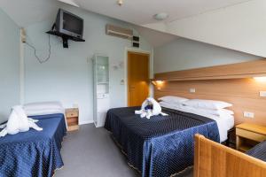 a hotel room with two beds and a tv at Hotel Mimosa in Lignano Sabbiadoro