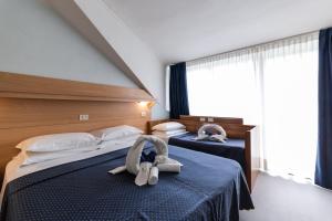 Dos camas en una habitación de hotel con animales de peluche. en Hotel Mimosa, en Lignano Sabbiadoro