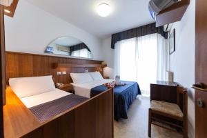 a hotel room with two beds and a chair at Hotel Vina De Mar in Lignano Sabbiadoro