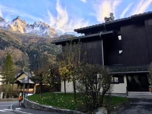 un bâtiment dans une rue avec des montagnes en arrière-plan dans l'établissement Aster, à Chamonix-Mont-Blanc