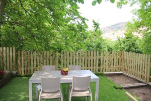 un tavolo bianco e sedie in un cortile con recinzione di Casa Vacanze Il Giardino - Appartamento Castagno ad Aritzo