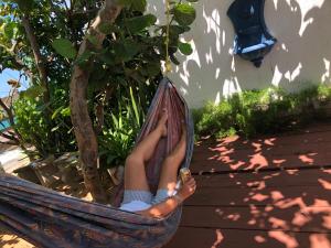 a woman sitting in a hammock next to a tree at The Beach Guesthouse in Pinones