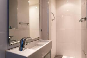 a white bathroom with a sink and a shower at Hôtel Le Mistral in Marseille