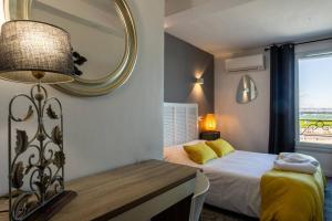 a bedroom with a bed and a mirror and a table at Hôtel Le Mistral in Marseille