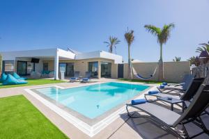 a swimming pool with chairs and a house at Sea Breeze Villas in Playa Blanca