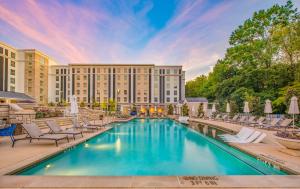 una piscina frente a un hotel con sillas y un edificio en The Guest House at Graceland en Memphis