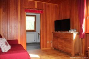 ein Wohnzimmer mit einem TV an einer Holzwand in der Unterkunft Sunlake Magneaz in Champoluc