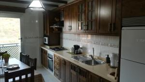 cocina con armarios de madera, fregadero y nevera en APARTAMENTO VISTAS DE ICOD, en Icod de los Vinos