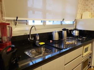 a kitchen counter with a sink and a stove at Edifício Vila Real in Balneário Camboriú