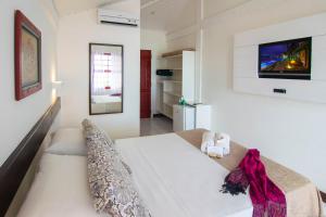 um quarto com uma cama e uma televisão na parede em Chez Pitu Praia Hotel em Búzios