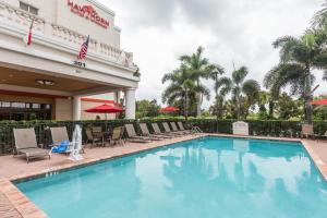 a pool at a hotel with chairs and umbrellas at Hawthorn Suites by Wyndham West Palm Beach in West Palm Beach