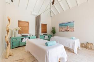 a white room with two beds and a sink at Dolphin Suites & Wellness Curacao in Willemstad