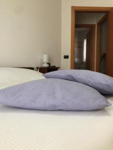 Una cama con almohadas moradas encima. en LA CASA DELLE CONCHIGLIE ombrellone, parcheggio e uso di biciclette gratis en Rímini