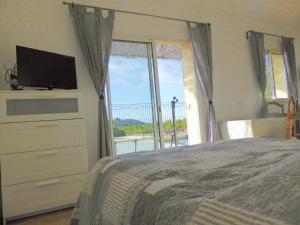 a bedroom with a bed and a tv and a window at La Provence in Vaison-la-Romaine