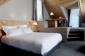 a bedroom with a large white bed and a staircase at Hôtel d'Angleterre in Arreau