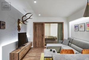 a living room with a couch and a tv at HREBIENOK MOUNTAIN APARTMENTS STARÝ SMOKOVEC in Smokovce