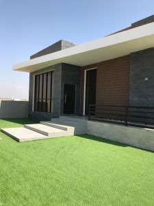 a house with a green lawn in front of it at platinum Chalet Mirbat in Salalah