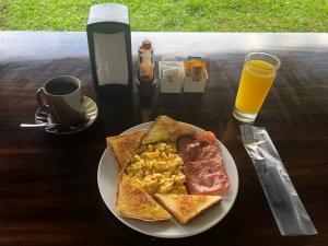 a plate of food with toast and eggs and a cup of orange juice at Hotel Villas Vista Arenal in Fortuna