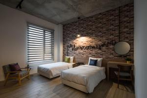 a bedroom with two beds and a brick wall at Tian Zhong Hotel in Tianzhong