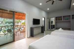 a bedroom with two beds and a balcony with a television at Casa Kaoba Hotel & Suites in Playa del Carmen