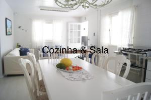 uma cozinha branca com uma mesa com uma taça de fruta em Casa com 4 quartos à 200 m da praia c/ churrasqueira em Palhoça